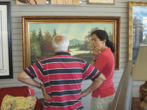 Customers discussing a large framed landscape painting