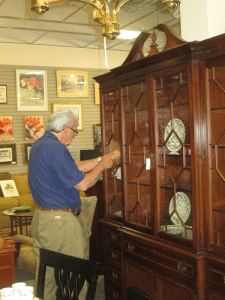 Man examining a large mahogany china cabinet with glass doors