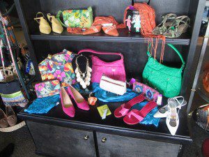 Colorful handbags, shoes, and accessories displayed on a black dresser