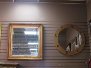 Two decorative mirrors hanging on a slatwall display