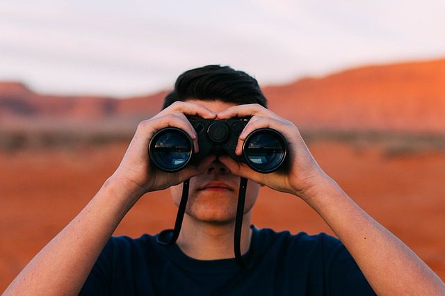 Person looking through binoculars outdoors