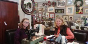 Woman and girl sitting at a table with a vintage sewing machine