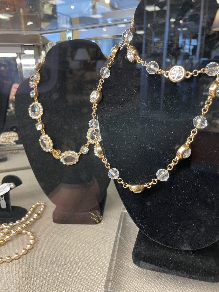Two crystal and gold necklaces on display busts
