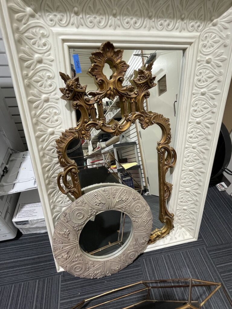 Ornate framed mirrors leaning against a wall